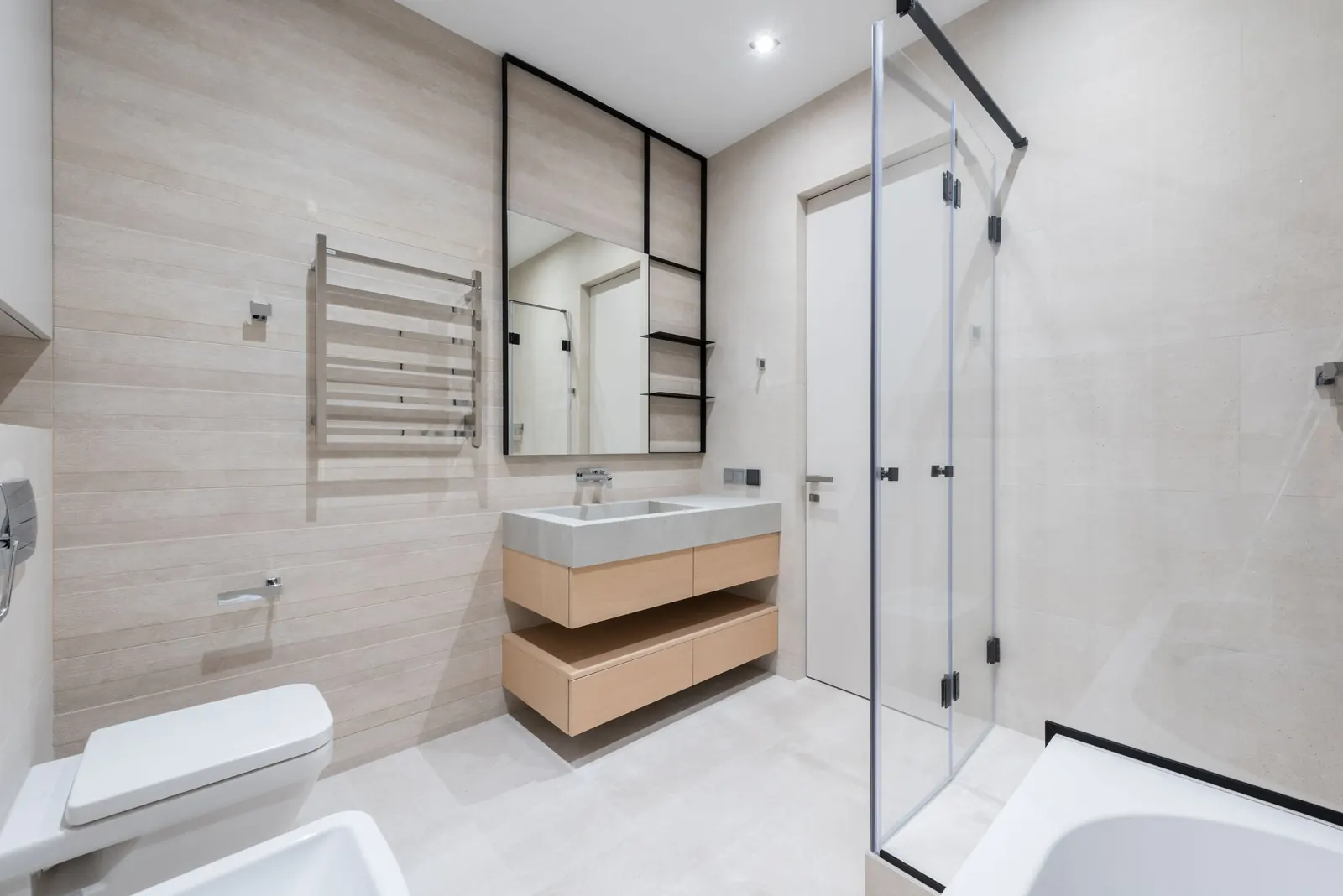 Bright, spotless bathroom with a wooden vanity, glass shower and beige tiles