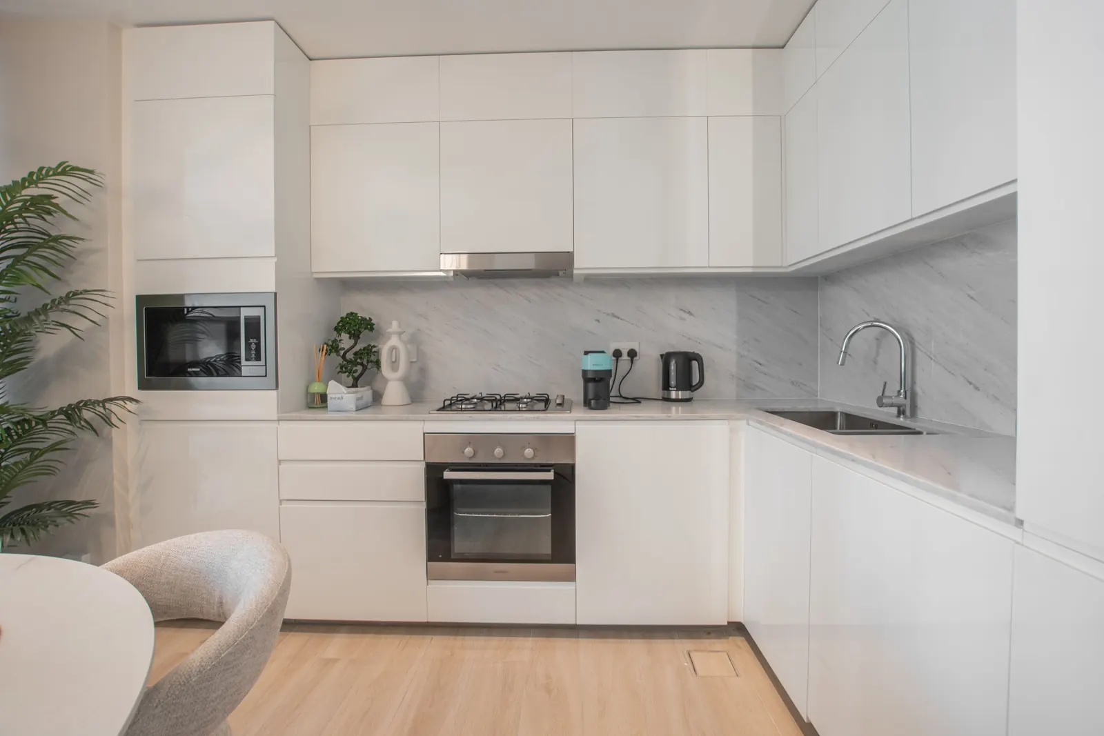 Clean modern white kitchen with marble-look backsplash and light wood floor