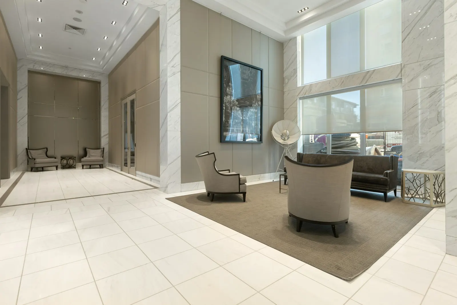 Bright, clean building lobby with marble-look floors, armchairs and tall windows